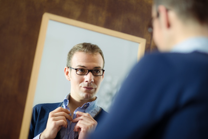 un homme qui s'habille devant un miroir