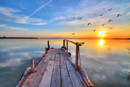 un ponton dans la mer avec le soleil à l'horizon